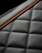 Macro of the diamond-quilted grey fabric with orange piping accent