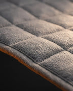 Macro of the soft gray quilted fleece surface and stitched edge of the heated pad