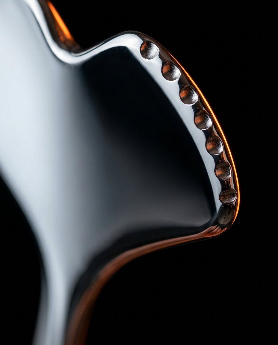 Macro of the facial tool's scalloped sculpting edge on polished steel