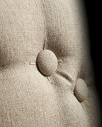 Macro of the tufted fabric buttons on the beige backrest cushion