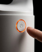 Finger reaching for the power button ringed in glowing orange on the fan