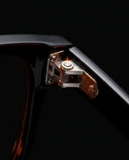 Macro detail of the spring-loaded stainless steel hinge on the glasses frame