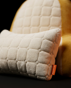 Detached cream quilted lumbar support cushion close-up with brand tag