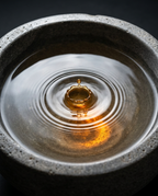 Golden essential oil drop rippling in water inside the stone aroma bowl