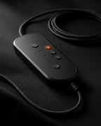Close-up of the wired massager remote with heat button glowing on a dark surface