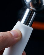 Close-up of a hand gripping the white silicone handle of the ice globe