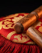 Close-up of the wooden strikers resting on the red and gold silk cushion