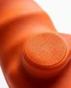 Macro of non-slip dotted texture on orange silicone grip pad surface
