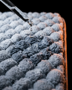 Water droplet absorbing into the bath mat pebble surface, macro shot