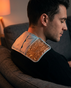 Man on a couch with the warm orange gel pack draped over his shoulder
