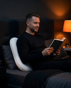 Man reading in bed with the V-shaped pillow supporting his back