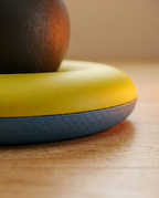 Yellow and blue stability ring base gripping a wood floor, low-angle detail