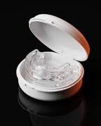 Mouth guard resting in its open white case on a reflective black surface