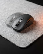 Macro of a wireless mouse gliding on the gray felt desk mat surface