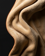 Soft tan fleece draped in flowing folds on a dark background