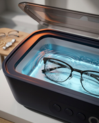 Black eyeglasses submerged in the ultrasonic cleaner's rippling water tank