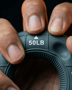 Fingers compressing the gray grip ring at the 50-pound resistance mark