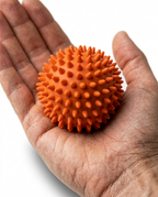 Open palm holding the orange spiky massage ball to show hand-sized scale