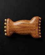 Top-down view of the wooden roller flat, brass beads lining both rolling ends