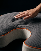 Hand leaving a slow-rebound memory foam imprint on the grey pillow surface