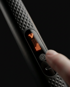 Close-up of the glowing OLED control display on the massage gun handle