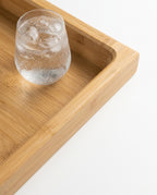 Macro of the raised-edge bamboo tray holding a glass of iced water