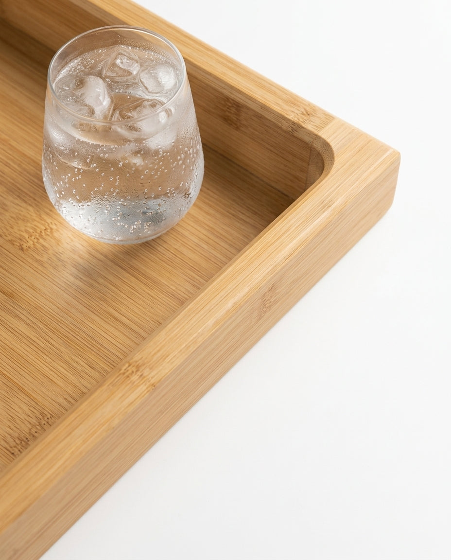 Macro of the raised-edge bamboo tray holding a glass of iced water
