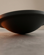 Side view of the balance board's curved rocker base on concrete