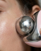 Close-up of the cold steel sphere gliding across skin with frosty vapor rising