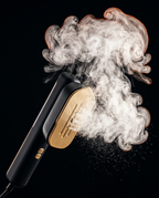 Garment steamer releasing a thick plume of steam on black background