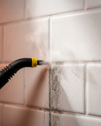 Steam nozzle blasting dirt from a tiled wall's grout lines
