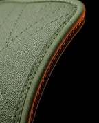 Macro of reinforced edge stitching and orange trim on the green grip pad