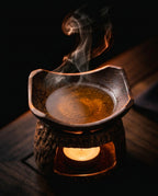Top dish of the ceramic burner holding warming oil with vapor rising