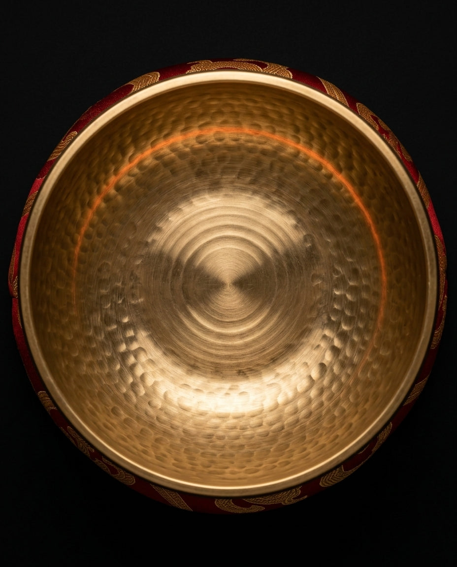 Top-down view inside the hammered brass singing bowl on its red cushion