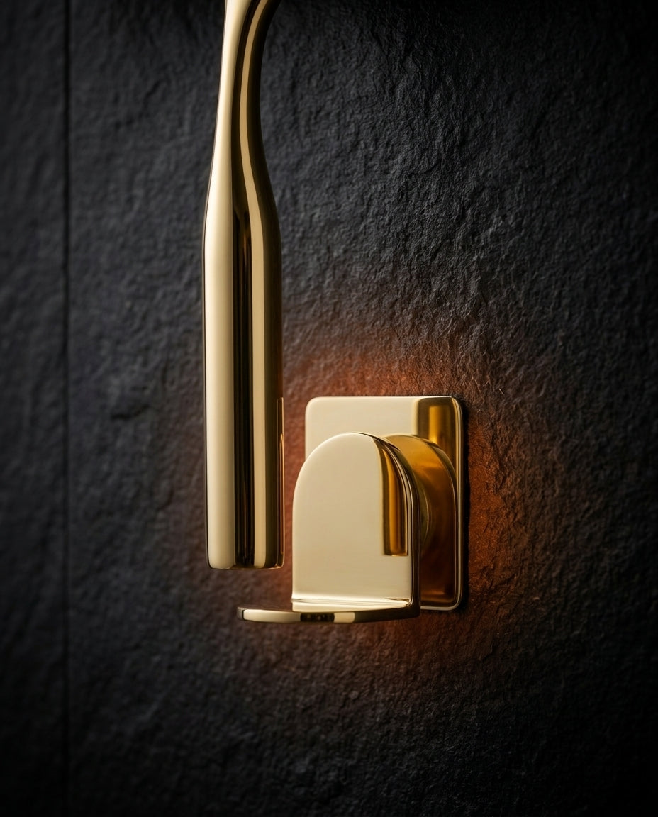 Brass squeegee handle hanging beside its polished brass adhesive wall hook