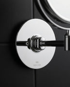 Macro of the round chrome wall-mount base plate on a dark tile wall