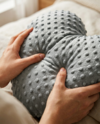 Hands holding the weighted heart cushion to show its grounding heft