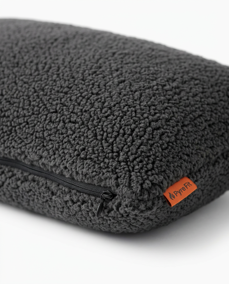 Corner of the dark grey sherpa lumbar pillow showing zipper and orange tab
