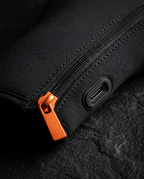 Macro of the orange zipper pull and USB-C charging port on the glove