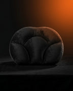 Black egg-shaped neck support pillow on dark surface with dramatic orange backlight