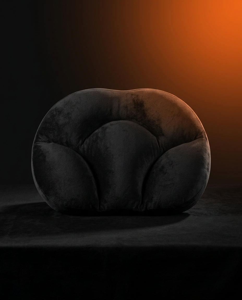 Black egg-shaped neck support pillow on dark surface with dramatic orange backlight