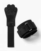 Black paw lifting grip flat-laid showing paw pad and metal D-ring strap
