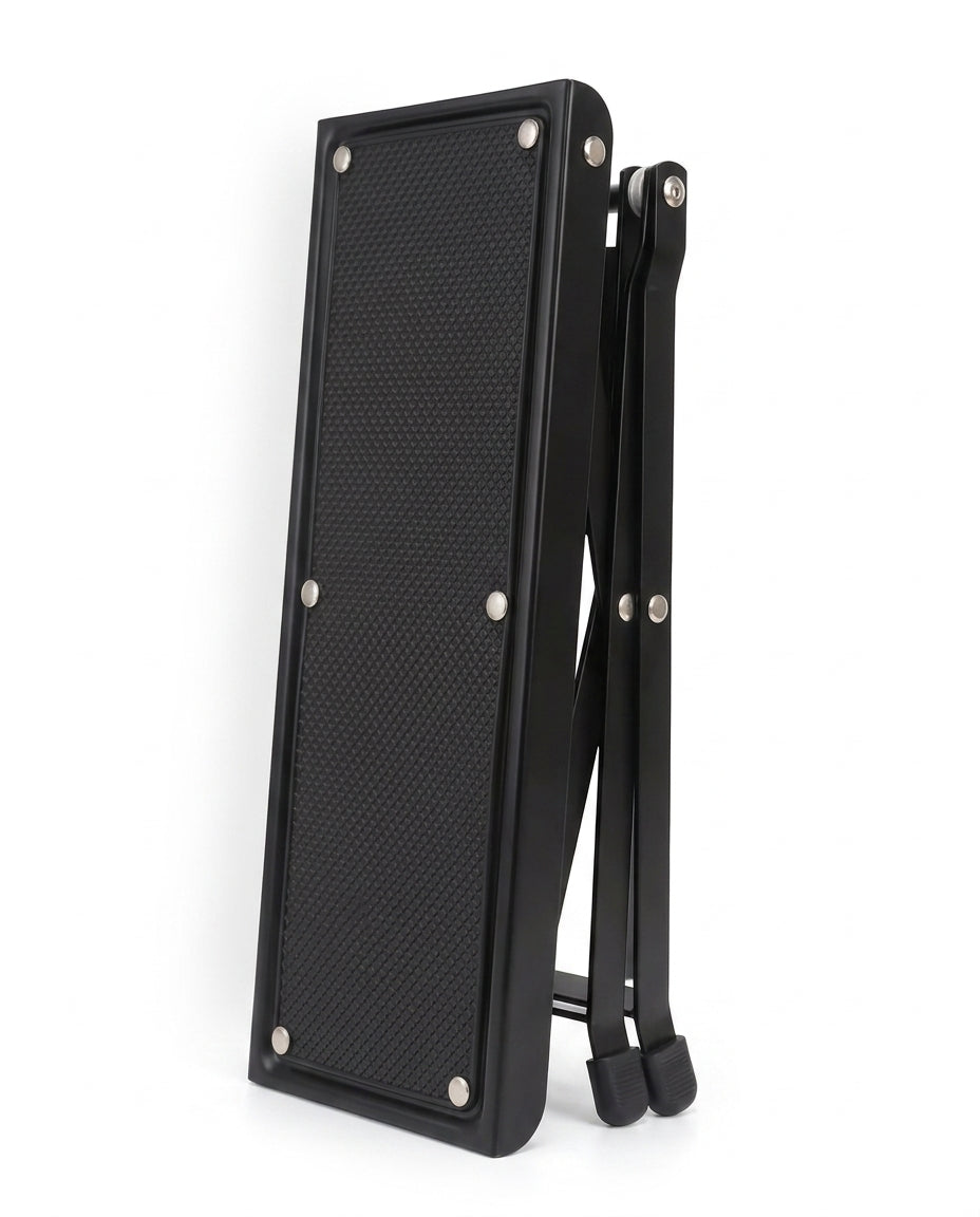 Black footrest platform folded flat for compact storage, on white
