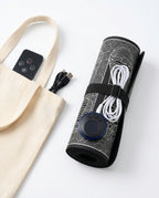 Foot massager mat rolled and strapped beside a tote bag, showing portability