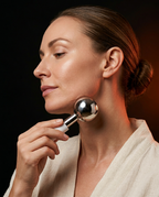 Woman sculpting her jawline with a chrome facial ice globe in profile