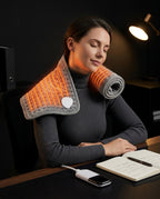 Woman wearing the heating pad over her neck and shoulders at a desk