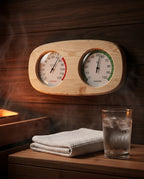 Sauna thermometer above folded towel and iced water glass in steamy sauna