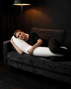 Woman lounging on dark sofa cradling the V-shaped support pillow