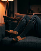 Legs in compression socks resting on a couch in a dim living room
