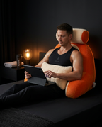 Athletic man relaxing post-workout with a tablet on the orange reading pillow